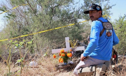 Roberto Resendiz kneels in front of a grave.