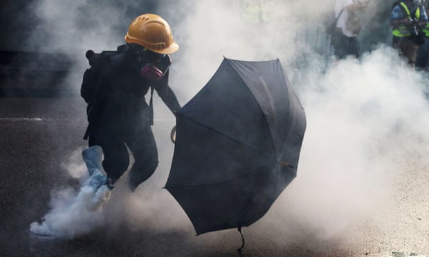 An anti-government protester picks up a tear gas canister during a demonstration in Hong Kong