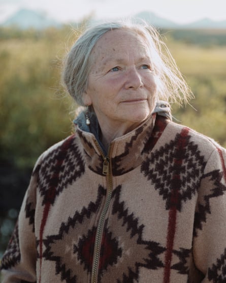 Woman with white hair pulled back, and fleece jacket zipped to neck.