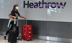 Passengers wearing a face mask or covering due to the Covid-19 pandemic, arrive at Heathrow airport