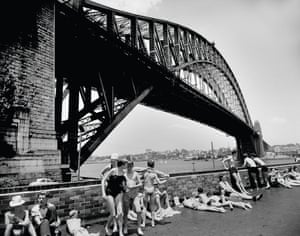 Milsons Point patrons enjoy a swim and a lie in the sun at the North Sydney olympic pool, against the backdrops of Sydney Harbour and the Harbour Bridge during the summer of 1956
