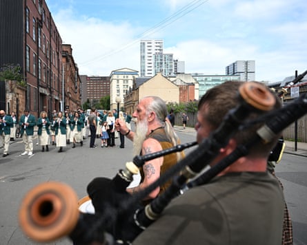 A bagpiper and a drummer playing for athletes.
