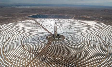 Solar panels arranged in concentric circles around a tower and power plant in a desert expanse