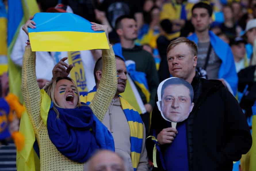 Ukraine fans, one holding a mask of Ukraine President Volodymyr Zelenskiy, cheer their team ahead of kick-off.