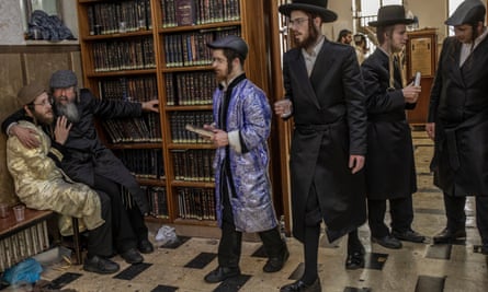 Men in Jewish religious clothing inside a room with books lined on shelves