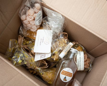 A box filled with products made from honey, including lip balm and throat syrup.