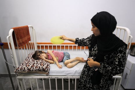 Nasma Ayad fans her daughter, Jana Ayad, who is malnourished, according to medics, as she receives treatment at a hospital in Gaza City.