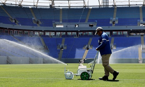 A member of staff works on the pitch as sprinklers spray water at Stadium 974, a venue for the 2022 Qatar World Cup
