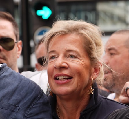 Closeup of Katie Hopkins in street surrounded by people; she has long blond hair tied back and wears dangly star-shaped gold earrings.