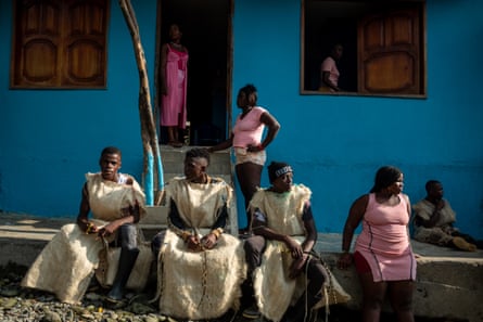 People sit in front of a home which is painted bright blue