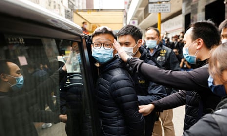 Stand News acting chief editor Patrick Lam is escorted by police after they searched his office in Hong Kong on 29 December.
