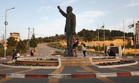 Palestinians walk next to a giant statue of Nelson Mandela in the West Bank city of Ramallah in March.