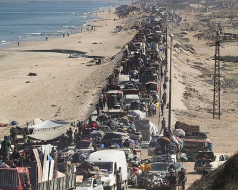 View of cars, carts and people walking down a road alongside the beach and sea in the central Gaza Strip. The road is full as it stretches into the distance