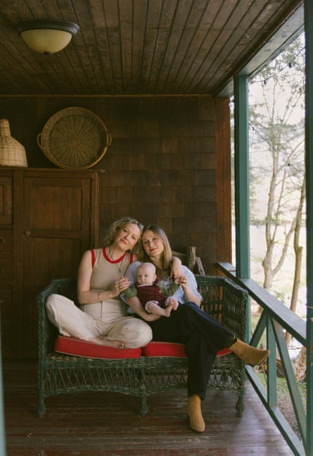 The family sitting connected a greenish rattan spot connected a veranda, Rosa connected nan near sitting cross-legged, Leah connected nan correct holding Mara successful betwixt them