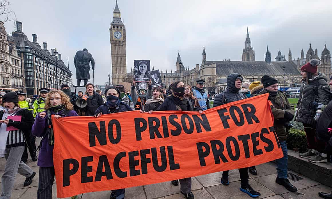 Protesters holding a banner outside parliament in London reading 'No prison for peaceful protests'