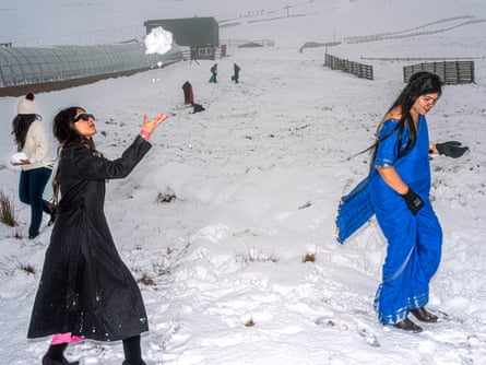 Two Asian women in snow, one with coat and the other wearing a blue sari