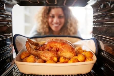 View looking out from inside an oven as woman cooks Sunday roast chicken dinner
