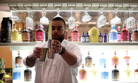 A bartender holds cocktail shakers in his hands.