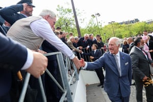 A man leans over a barrier to shake hands with Charles