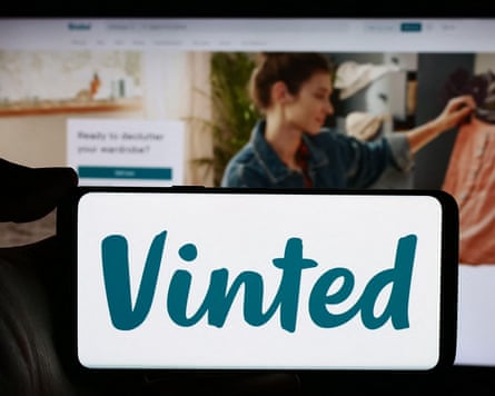 Person holding mobile with Vinted logo in front of its webpage