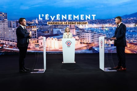 Benoît Payan and Franck Allisio stand at lecterns opposite each other in a TV studio, with Caroline Roux between them