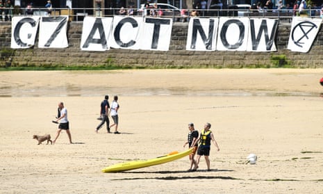 An Extinction Rebellion banner reads ‘G7 Act Now’ on a beach at St Ives, on Sunday.