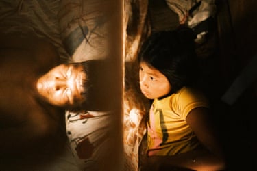 A child looks at a sleeping man.