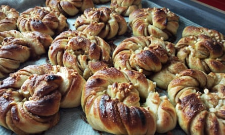 Top close-up view of homemade Swedish cardamom and cumin rolls on a oven tray.
