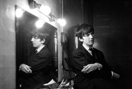 George Harrison poses beside a mirror backstage