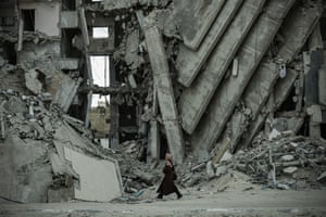A person walks past a huge collapsed concrete building