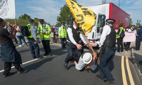 Police move a protester from the road as a truck tries to make a delivery to the DSEI arms fair in London.
