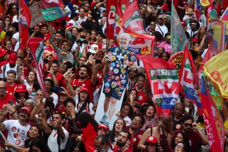 A crowd with Lula flags and a cutout of the Brazilian president adorned with stickers
