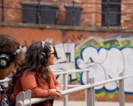 A closeup side profile of a woman wearing sunglasses and large over-ear headphones.