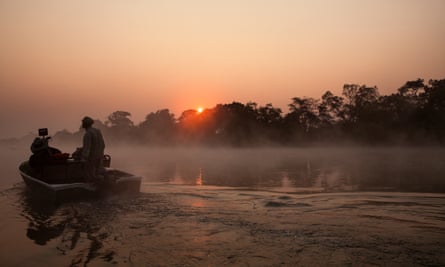 Tourist on boat tour on a misty morning. Kafue River, Kafue National Park, Zambia