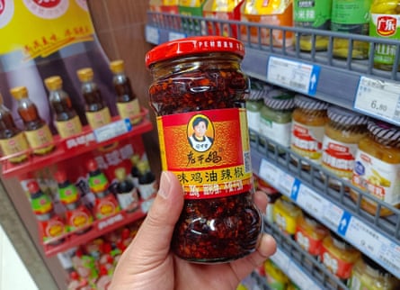 A hand holding up a jar of Lao Gan Ma chilli crisp in a supermarket