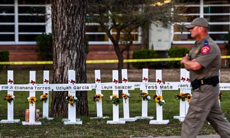 Police officers walk past a makeshift memorial for the shooting victims at Robb Elementary School in Uvalde, Texas on 26 May 2022.