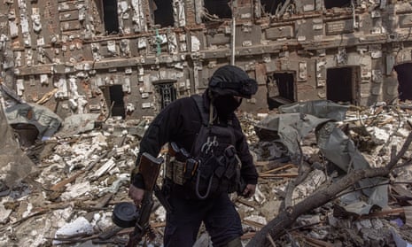 A member of the Ukrainian military walks on debris next to damaged buildings in Kharkiv