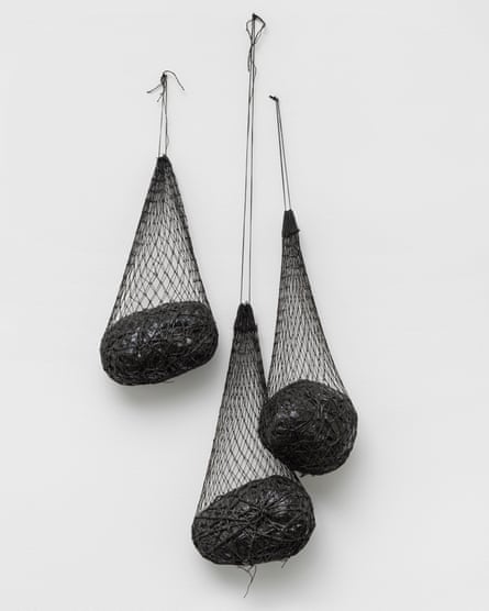 A sculpture made of nets, enamel, string, paper, metal and cord, with heavy objects hanging in the nets, by Eva Hesse.