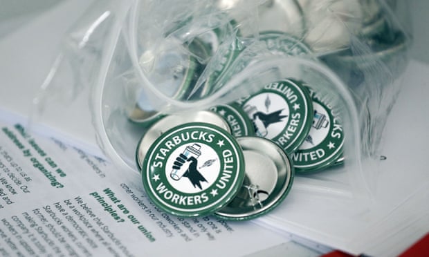 pins say ‘starbucks workers united’ in a green circle, like the company’s logo, but with a hand in the middle holding a bottle