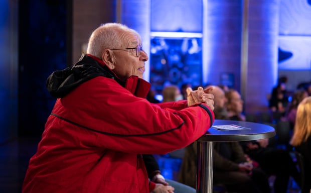 Profile of Dr Karl Krzelnicki at the Beaker Street Festival in Tasmania. He has short gray hair and wears glasses and a red jacket with a black hood.