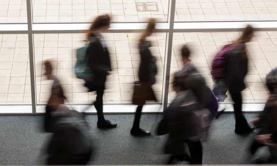 blurred secondary school pupils moving by a window in a school