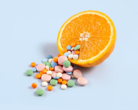 Vitamin pills on blue background with an orange