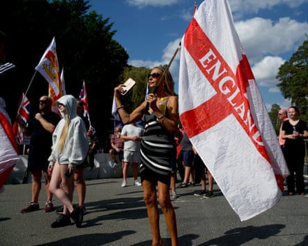A woman stands outside RAF Barnham holding a large England flag