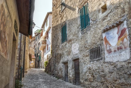 A narrow stone street with murals lining the walls