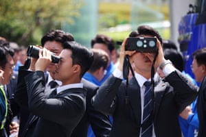 Two security personnel look through binoculars in different directions