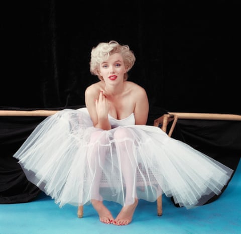 Marilyn Monroe is seen in a ballerina satin dress sitting on a wicker chair