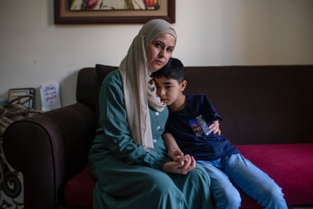 A woman hugs a small, sad-looking boy to her side.