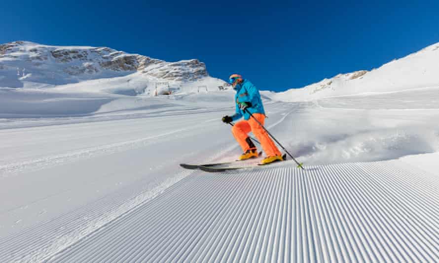 Young man skiing downhill in Alps. Beautiful clear blue sky. Winter sports and recreation.
