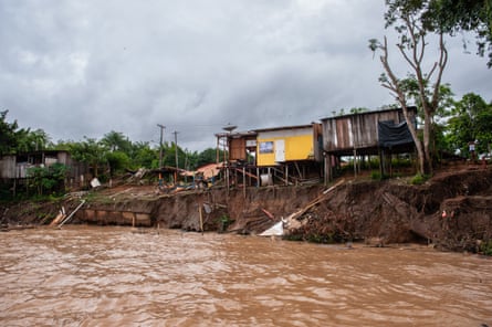 A muddy torrent of water runs past a group of collapsing houses.