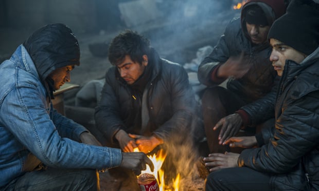 Refugees warm themselves by the fire in a derelict warehouse where they live in Belgrade, Serbia.